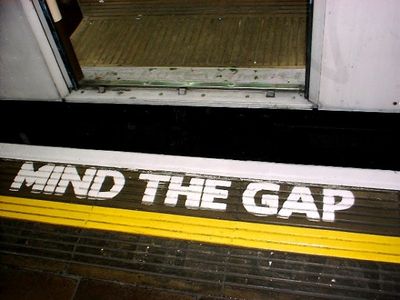 Yellow 'Mind the gap' warning painted on a curved London Underground platform edge